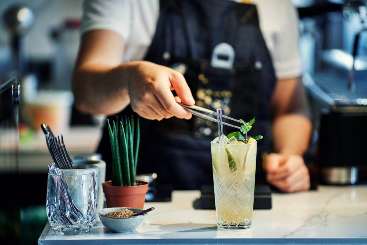 Close up of bartender mixing cocktail garnished with fresh mint leaves