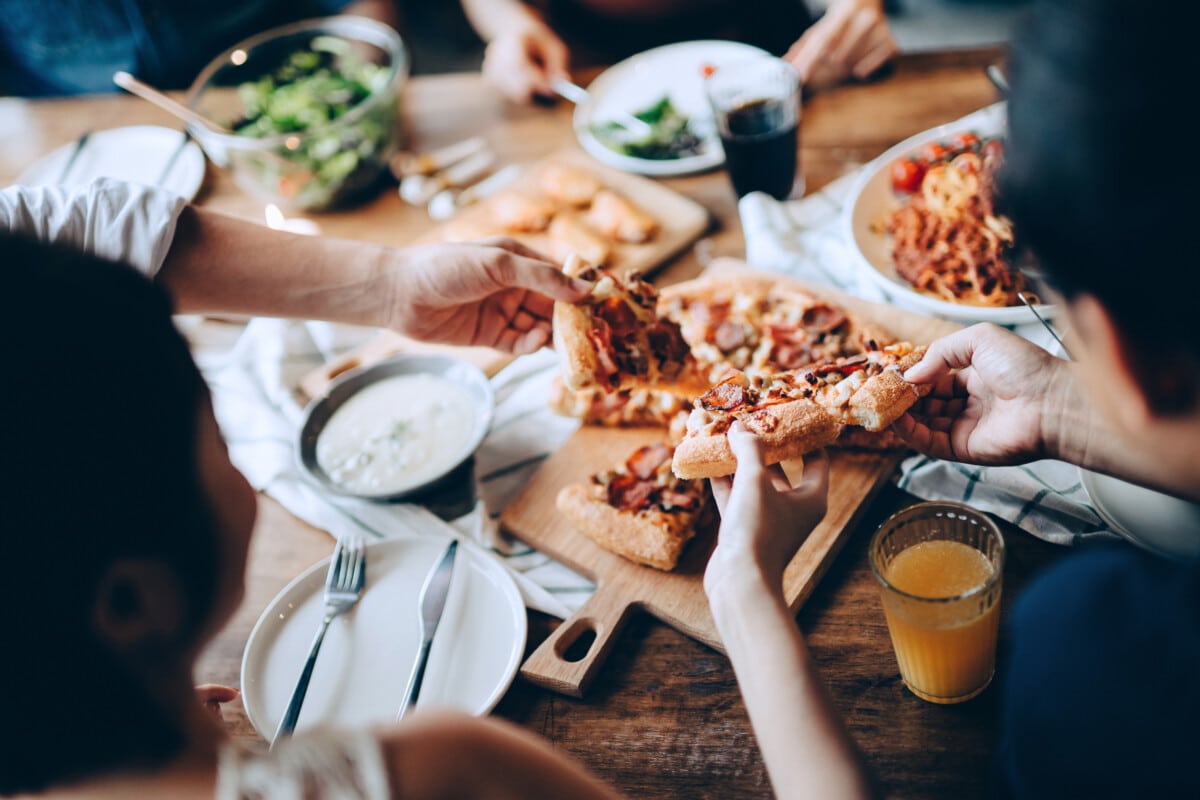 close up of pizza and other light appetizers being shared amongst a group of people