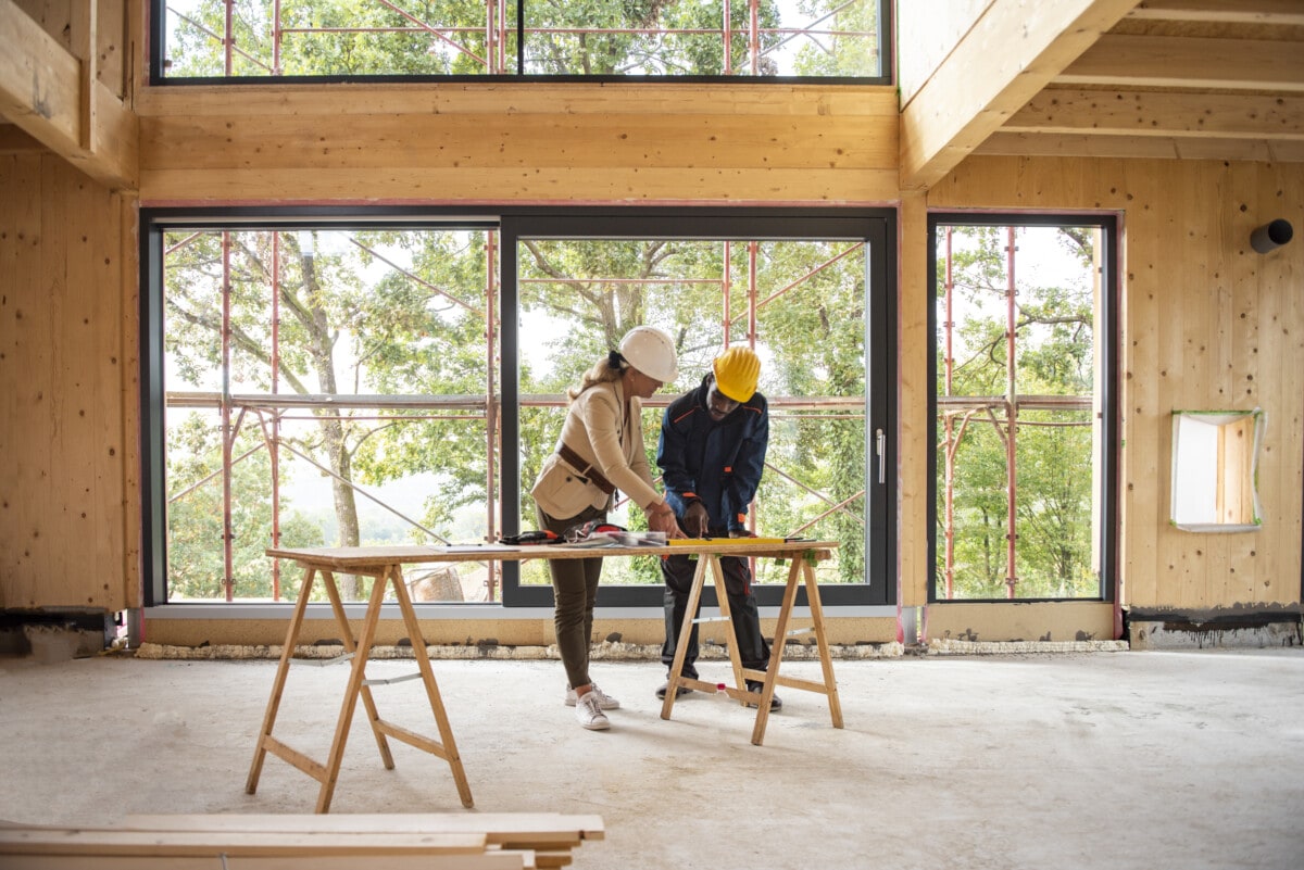 Team of women architect and men construction worker at  construction site. They are looking at blueprint. They are discussing about their project.