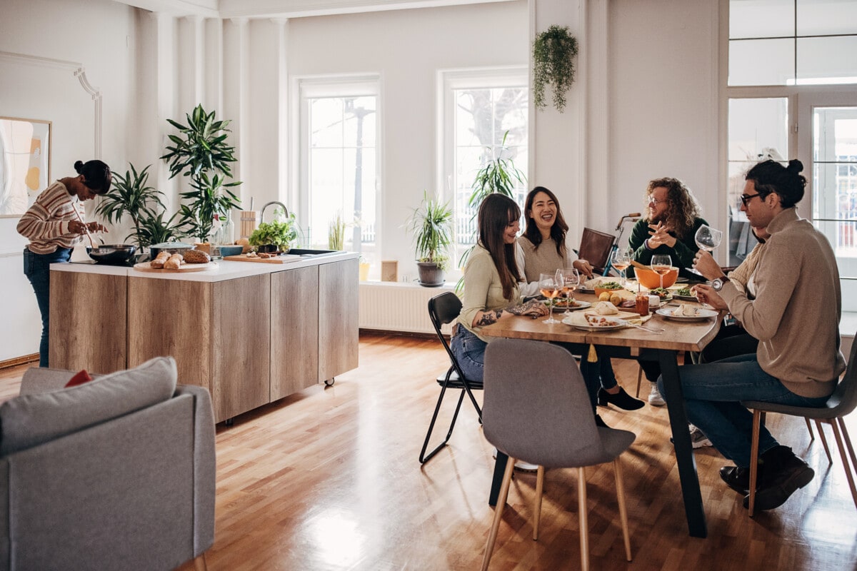 Group of friends sitting together on dinner party in modern home,