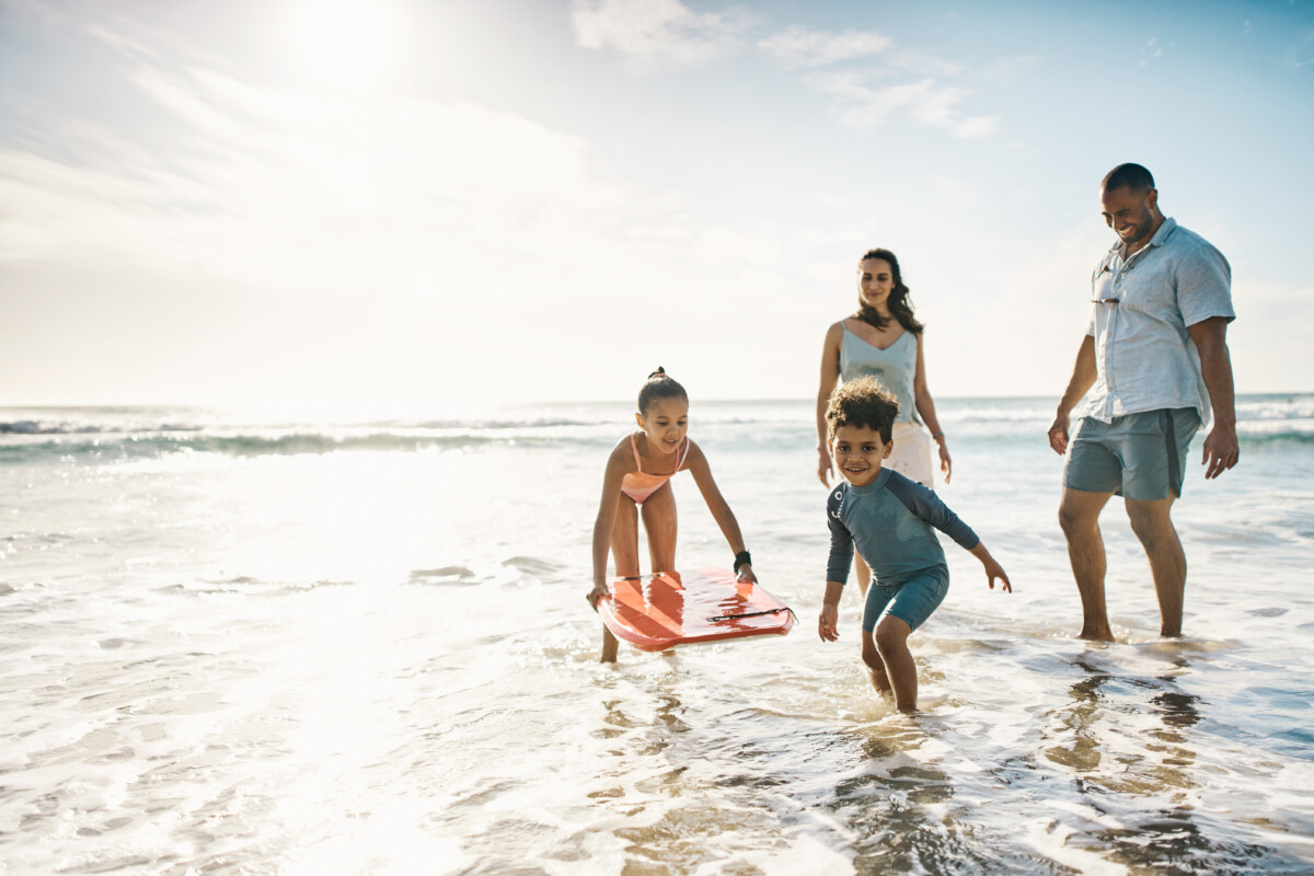 man and a women in the beach with two children