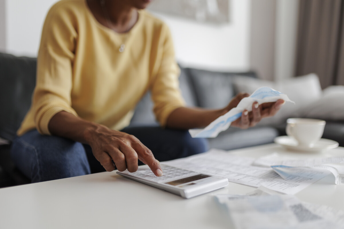 person sitting on couch while checking their bills on a calculator