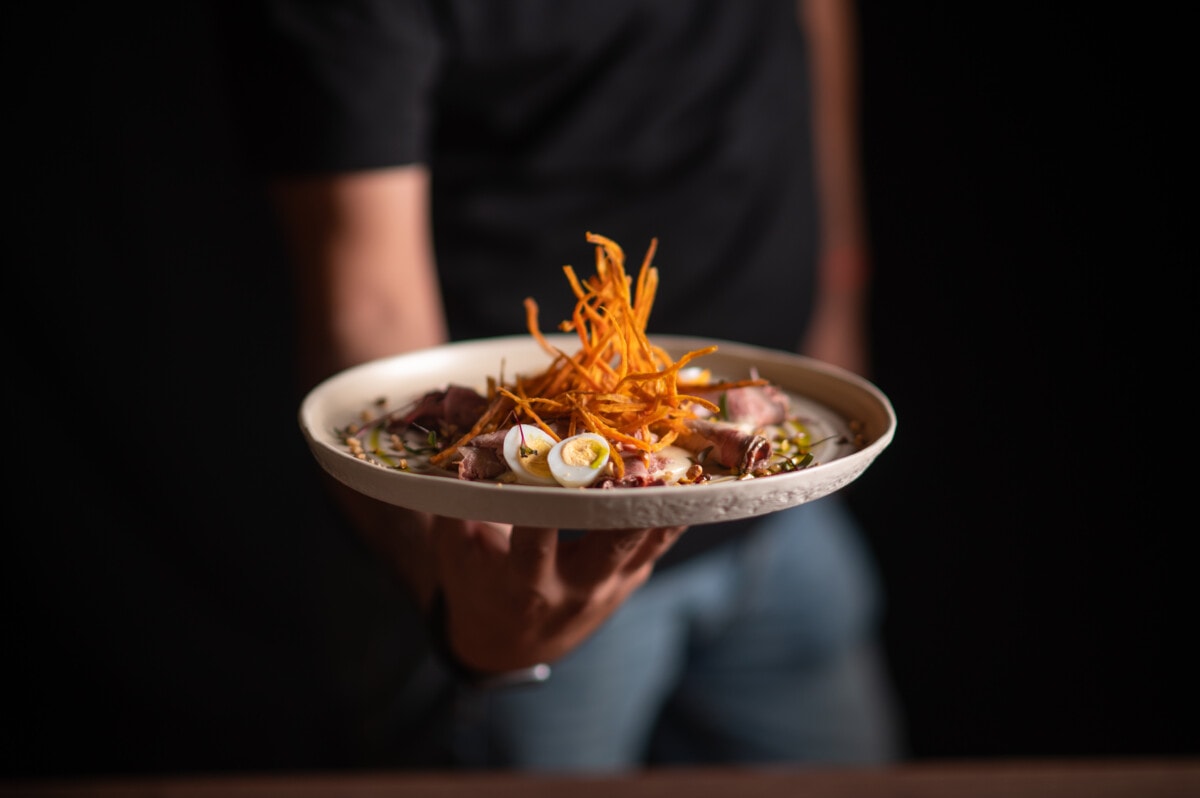 A male chef serving a fine dining dish in a restaurant.