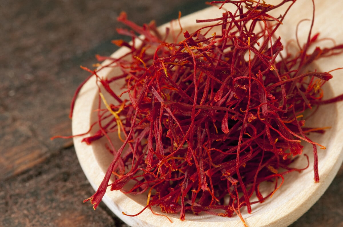 Macro shot of saffron in a wooden spoon on a textured wood background