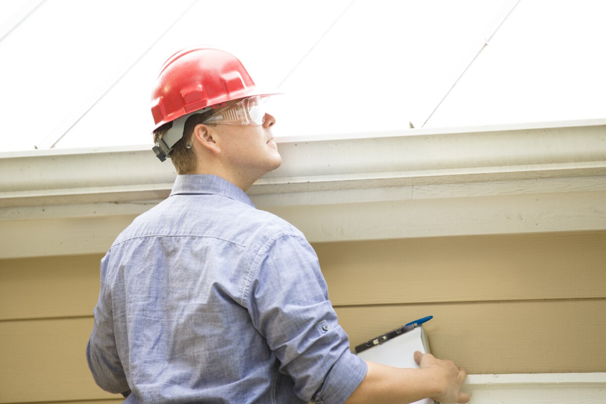 man conducting a home inspection on the roof with paper and pen_Getty