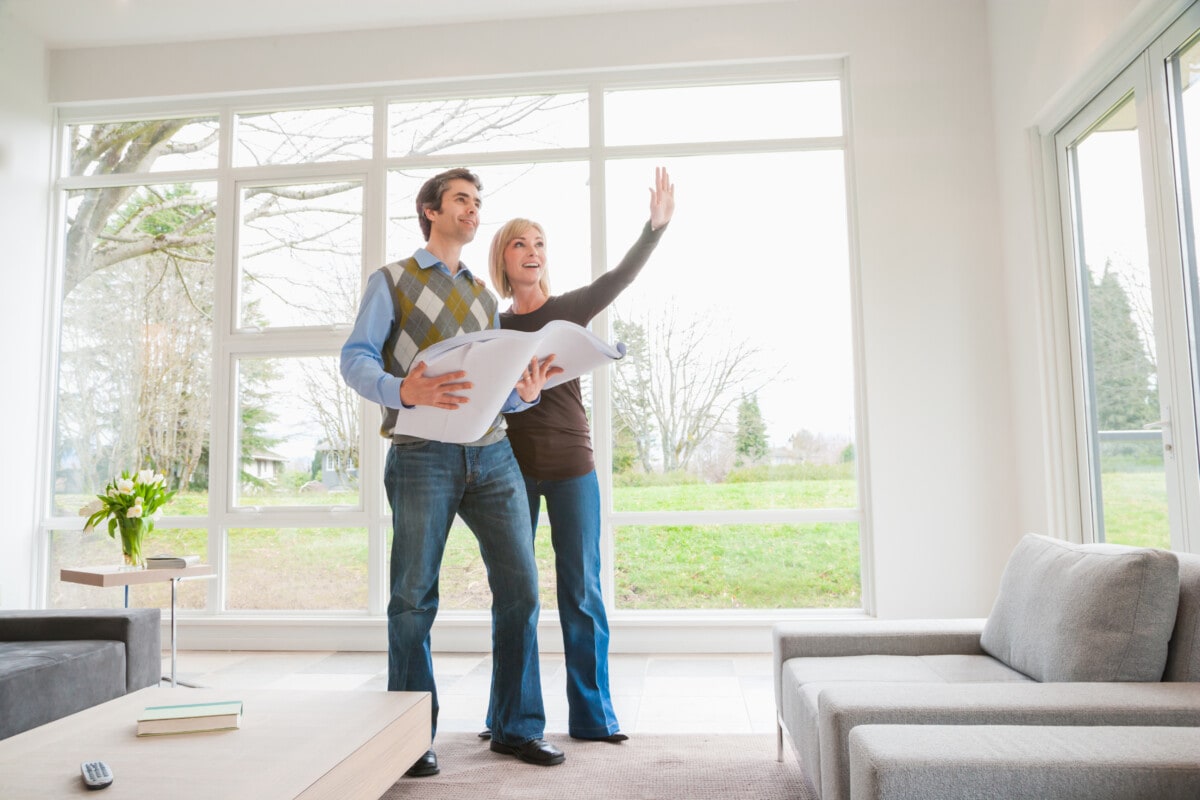 Man and a woman holding building plans and discussing remodel