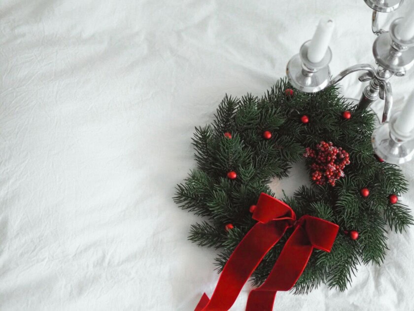 A holiday wreath with a red bow and faux berries