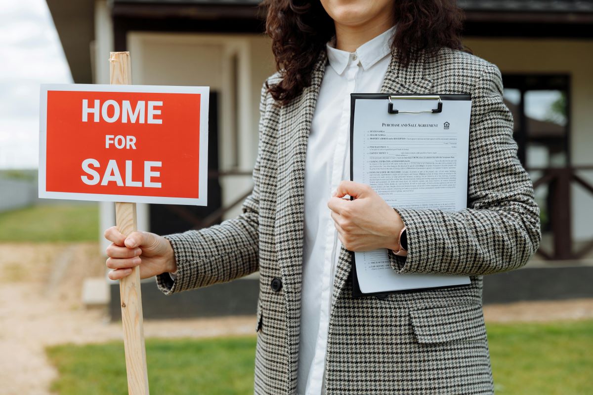 Woman holding for sale sign illustrating a seller accepting another offer while under contract.