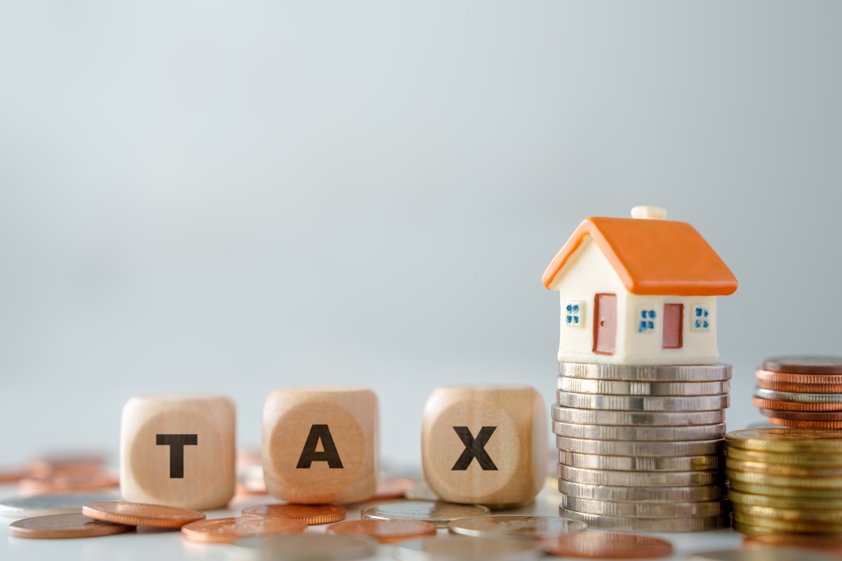 House model on growth of stack of coins and wooden blocks text TAX. Background for prepare budget for reduce property tax, Land transfer taxation and Investment income tax from asset.