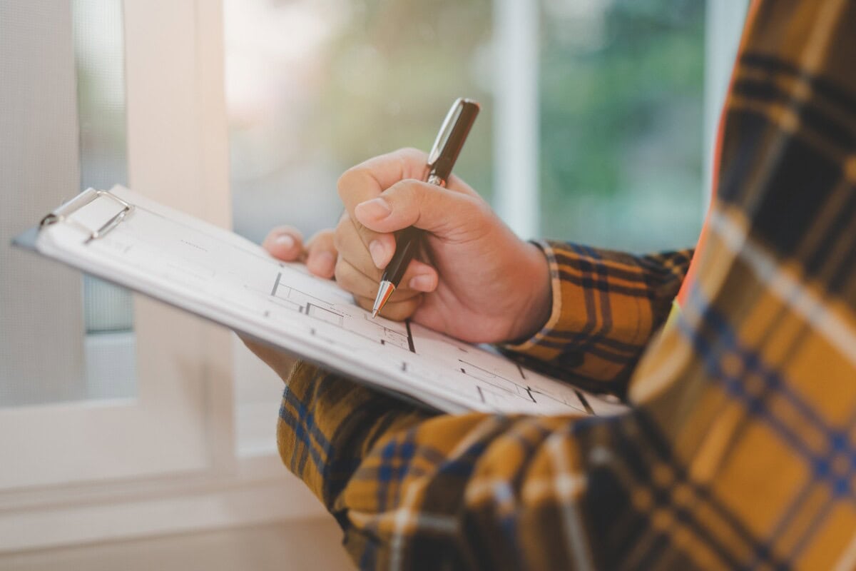 A person writes some things down on a notepad as they inspect a home.