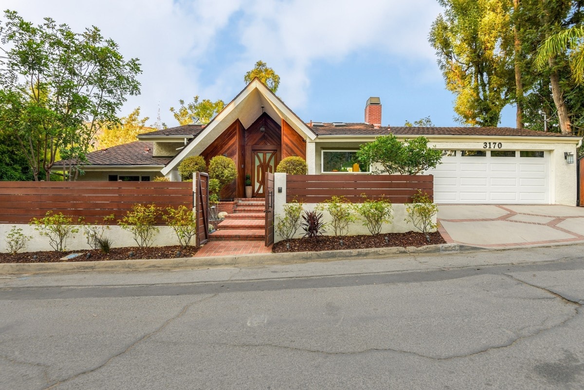 Neutral colored mid century modern home with triangle-shaped entry and wood fence