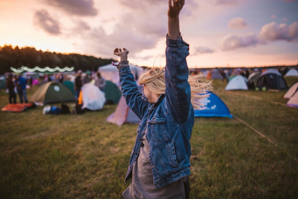 Woman dancing at a festival with tents in the background