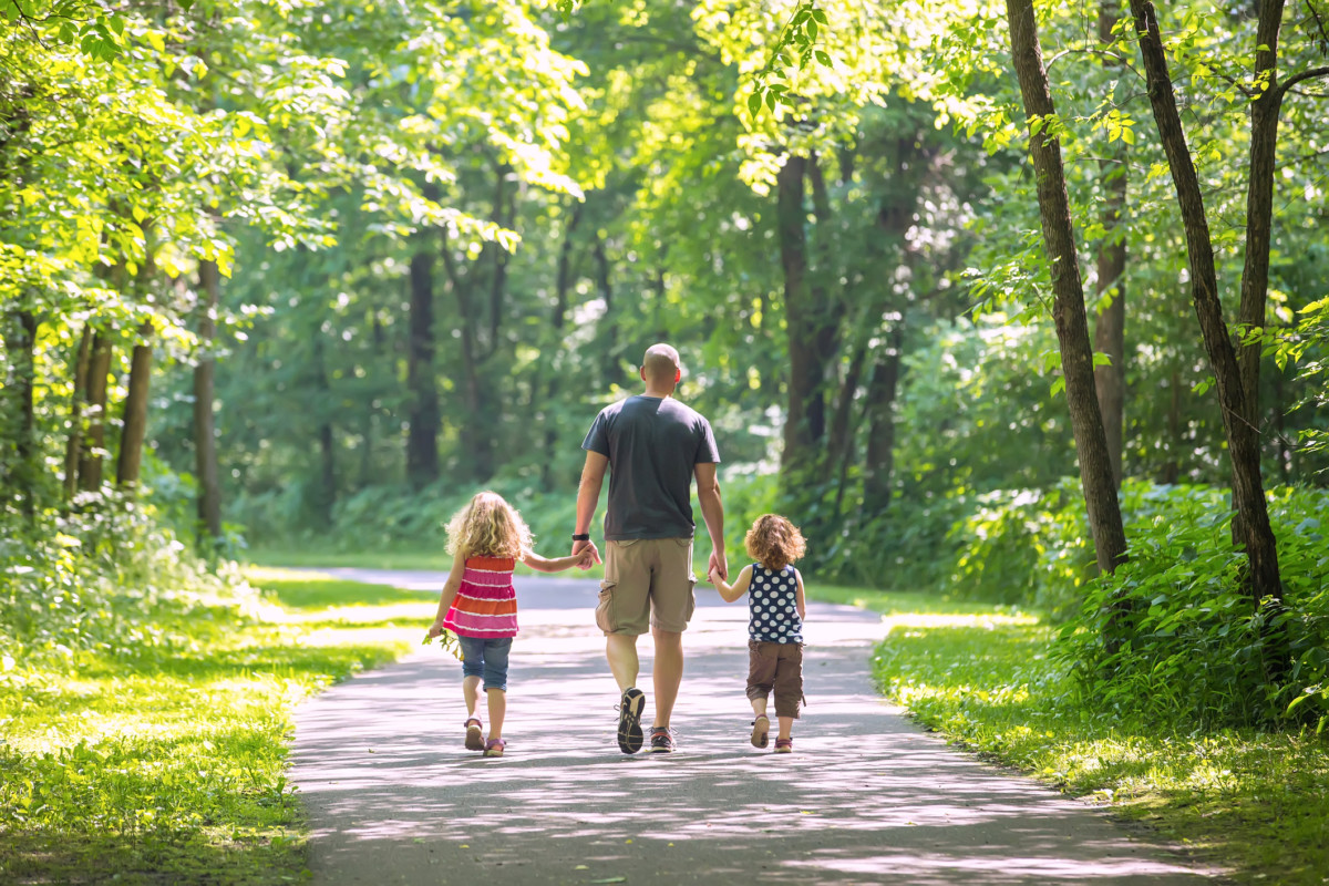 Father And Two Daughters Walking Through Woods at Park