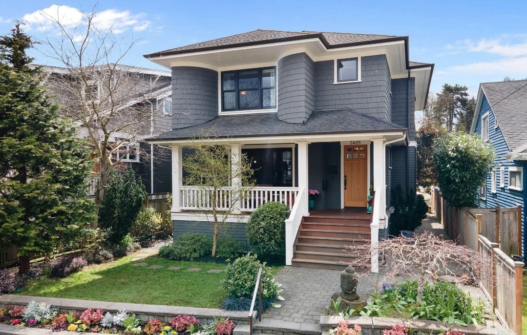 Two story grey house with front porch, white accents, and wood door