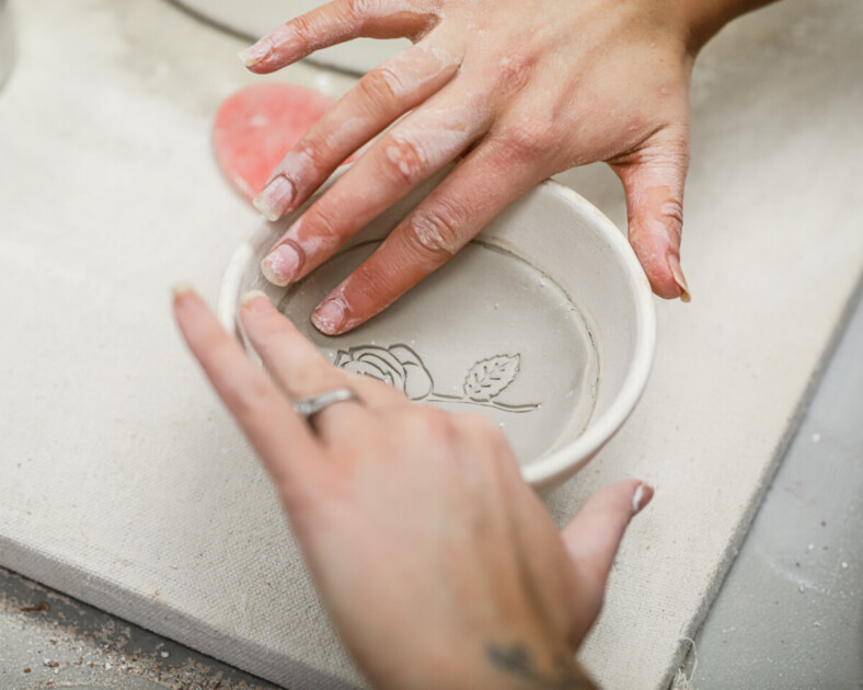 hands carving out clay to make pottery