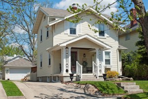 A smaller, older home with ornate porch features with a long driveway and many windows