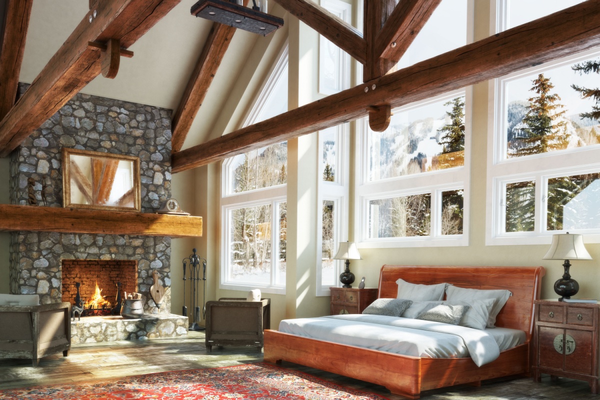 Cabin-style house with custom bed frame next to a stone fireplace 