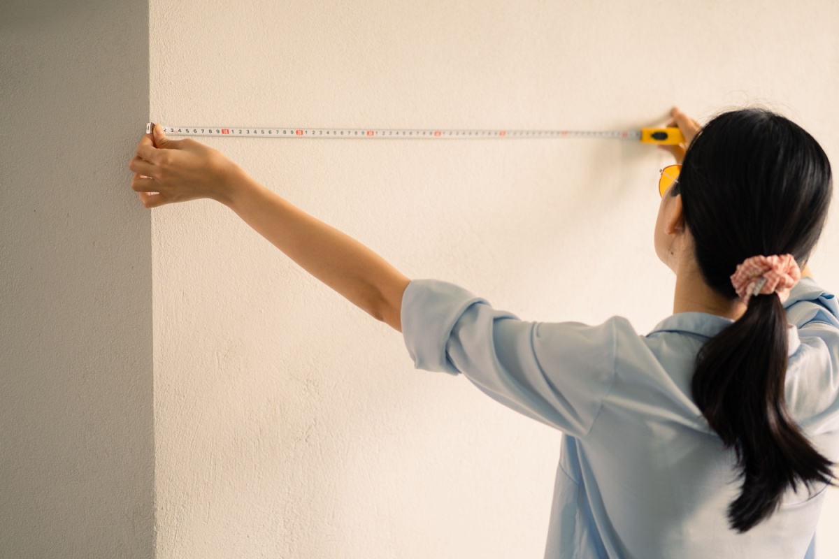 Woman using a tape measurer before beginning her unpermitted home repairs