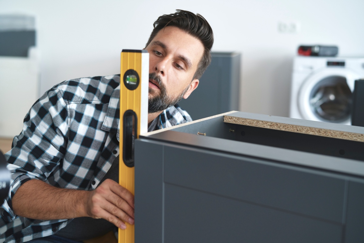 Inexperienced handyman levels the side of a cabinent
