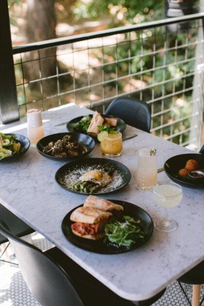 Food and cocktails on a table overlooking the San Luis Creek at Sidecar, a summer thing to do in San Luis Obispo