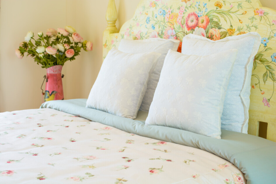 A bright bedspread with flowers on the bedside table