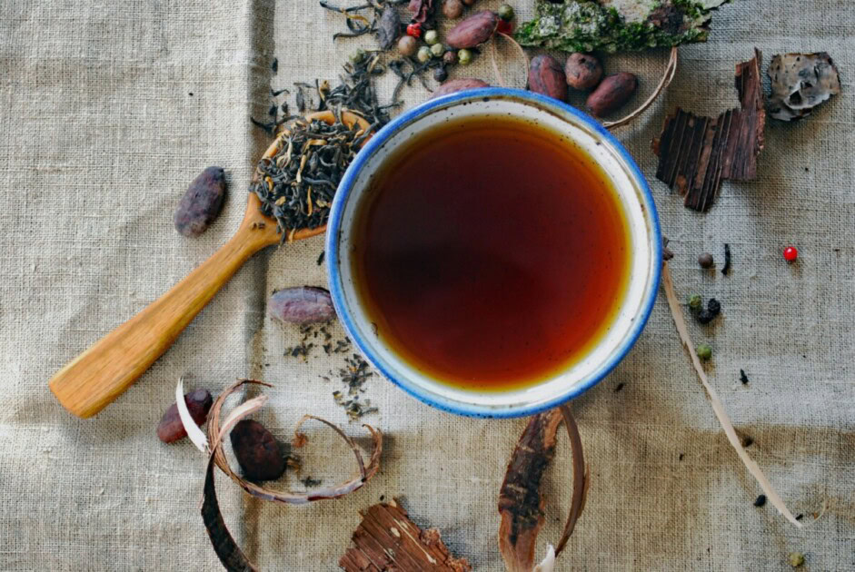 Loose leaf tea sits on spoon next to a mug of tea