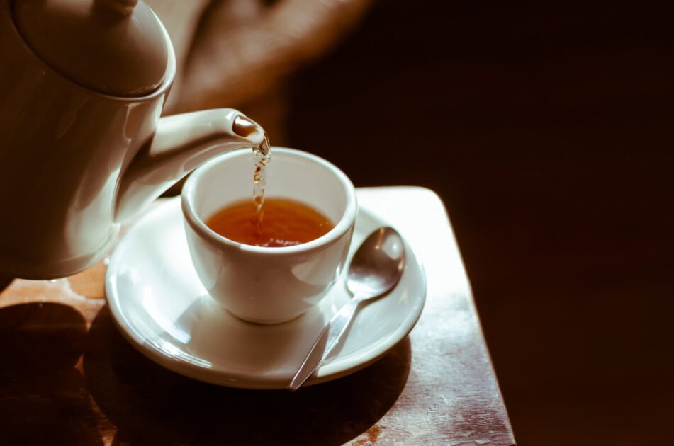 Warm tea is poured into a mug from a tea kettle