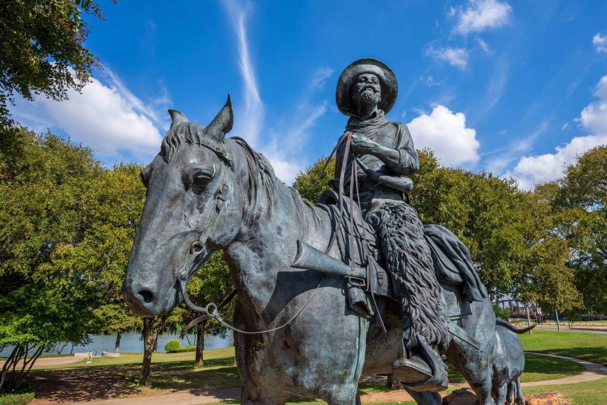 Detail of one of the cowboys driving longhorn cattle on the Chisholm Trail titled Branding the Brazos, Drover and Longhorn by Robert Summer in Indian Springs Park.
