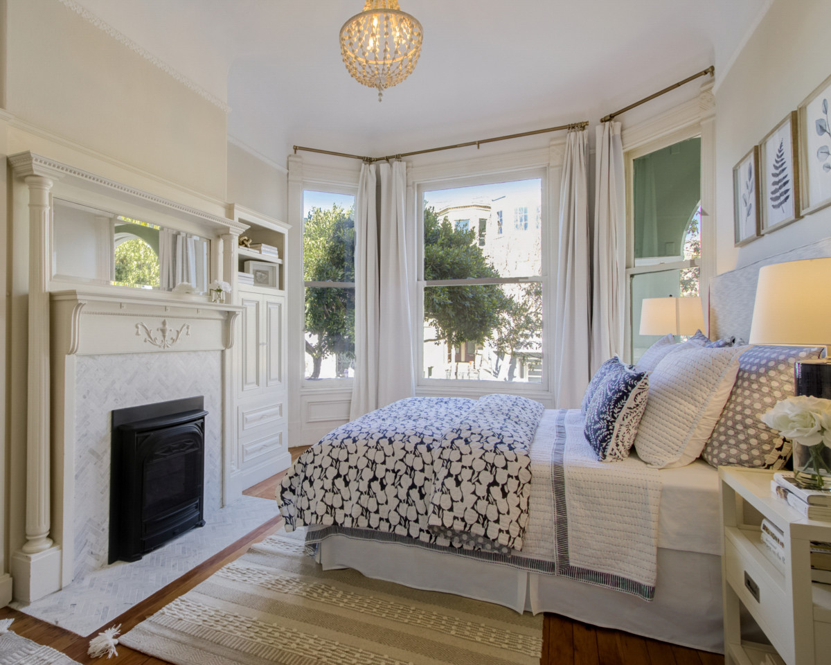 small bedroom with large windows and a fireplace