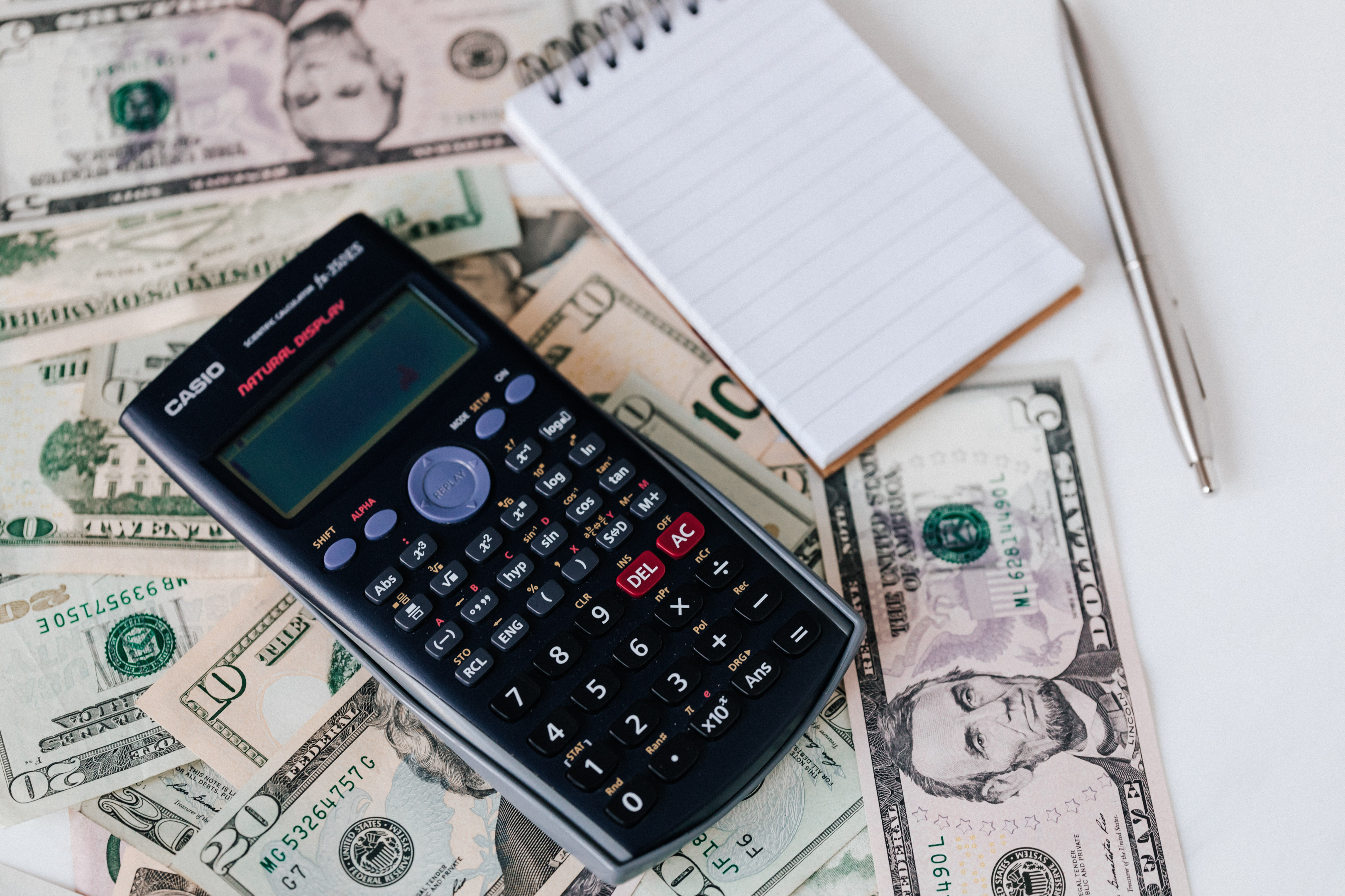 Calculator and notepad placed on dollars