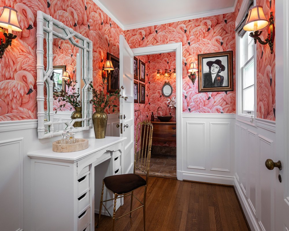 Powder room vanity area featuring vibrant pink flamingo pattern wallpaper and white wood paneling.