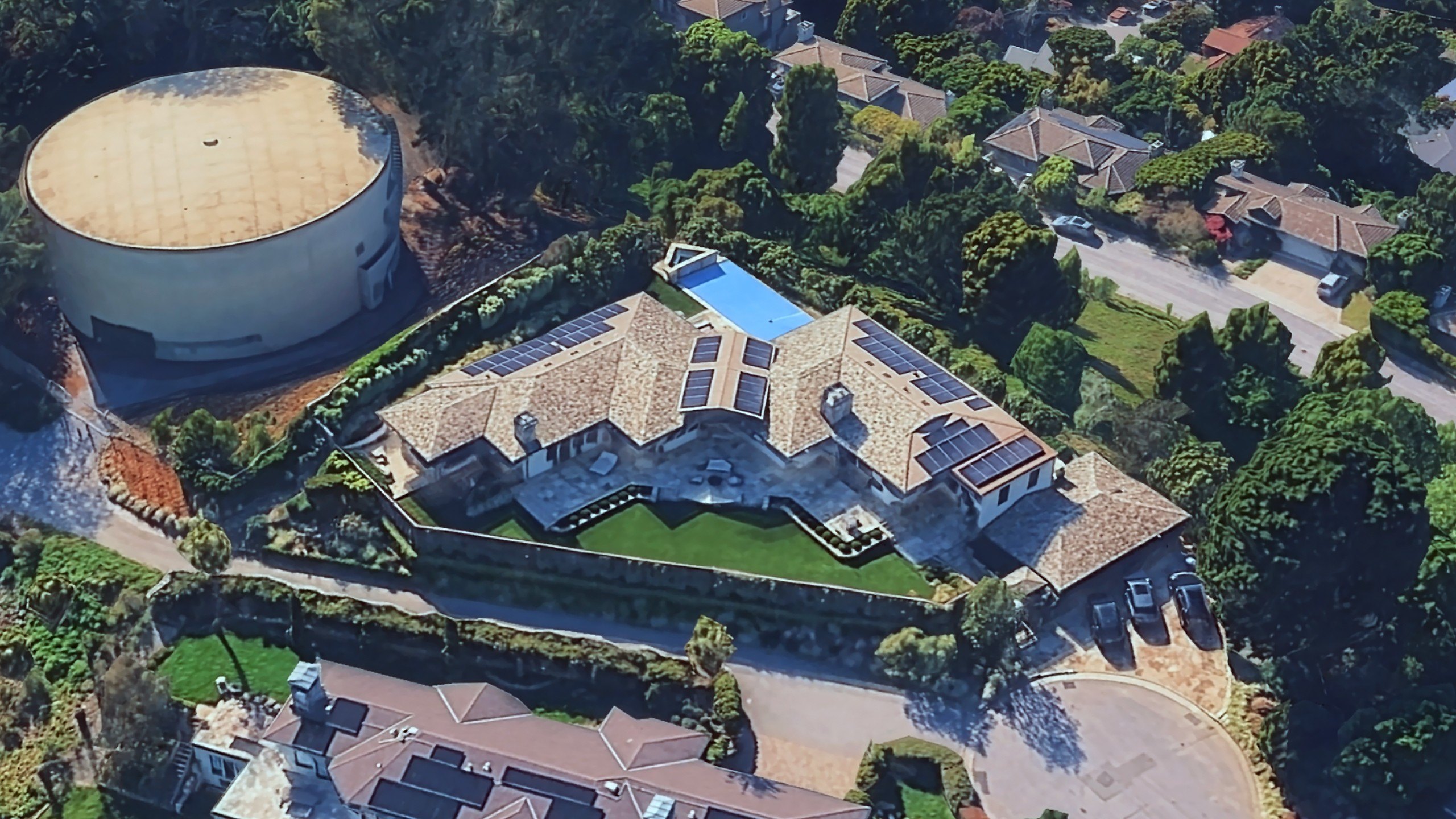 A split image shows an aerial view of a sprawling Mediterranean-style luxury estate with solar panels and a swimming pool.