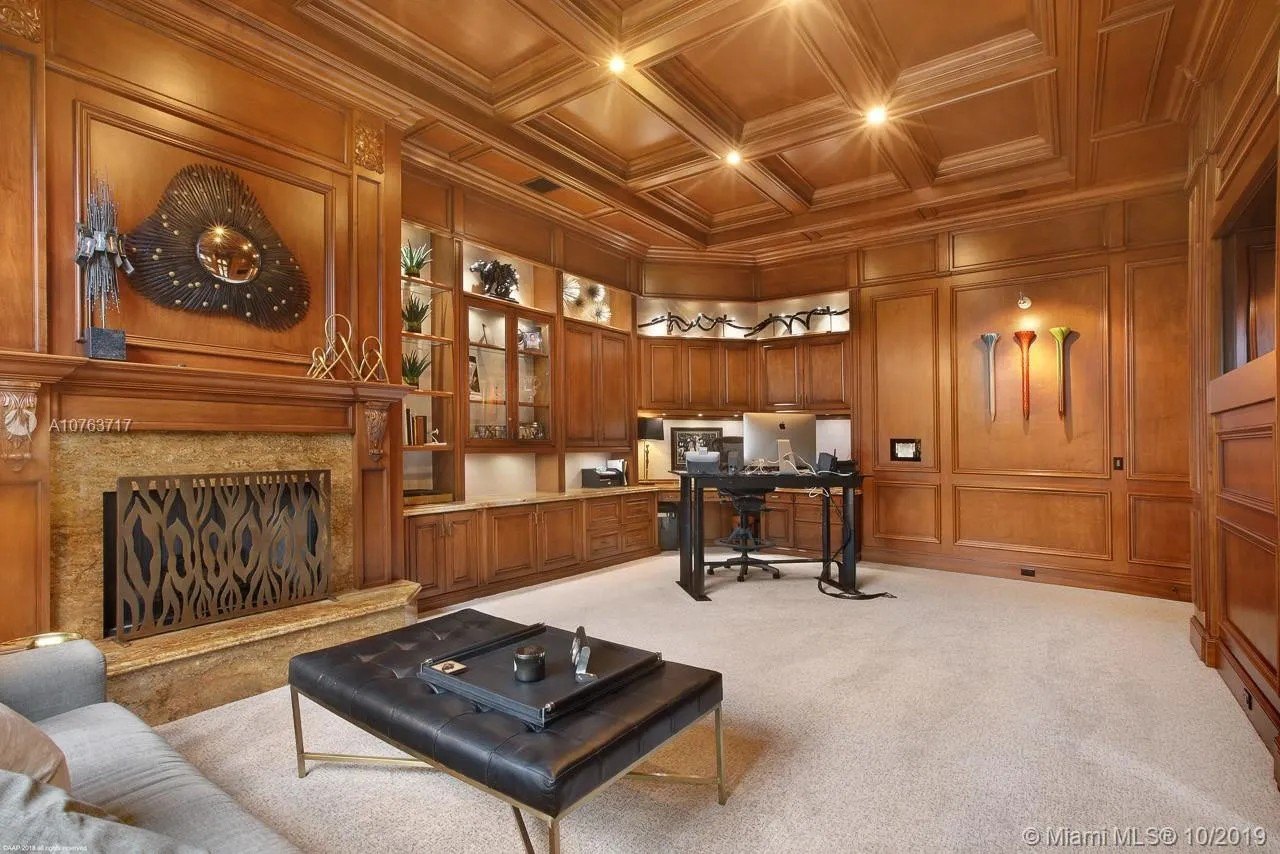 A wood paneled room with a fireplace in Greg Normans Palm Beach Mansion