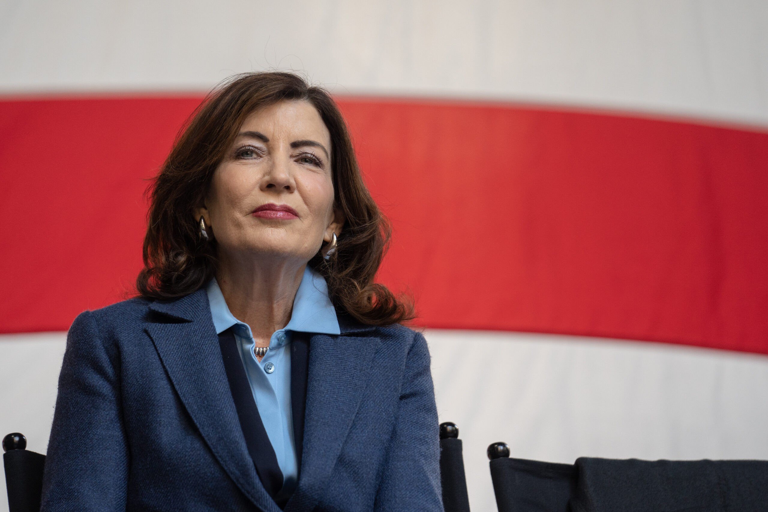Kathy Hochul, governor of New York, smiling with red and white stripes in the background