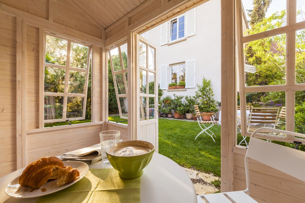 Breakfast table in a garden shed with a newspaper, croissant, water and coffee