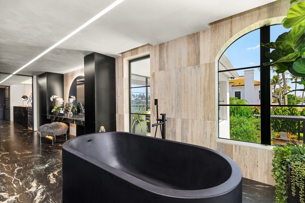 Luxury Primary Bathroom with Black Freestanding Soaking Tub and Travertine Walls