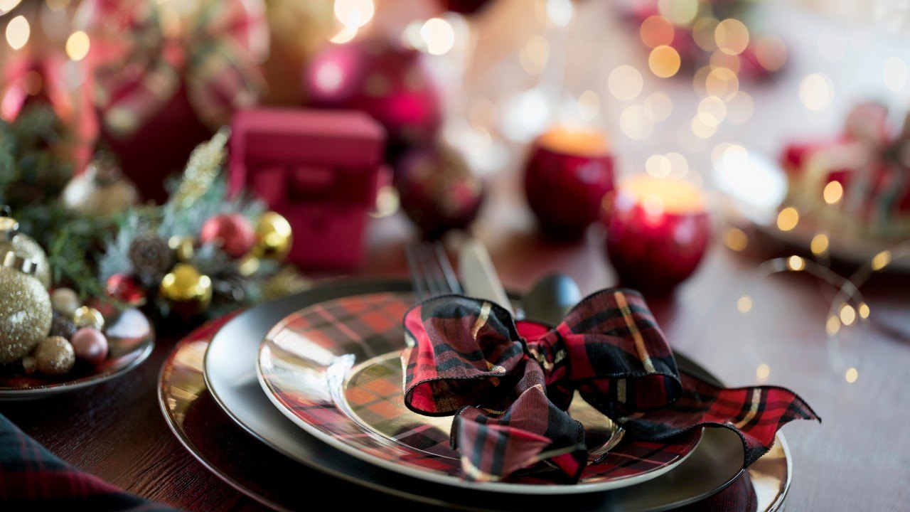 A dining table set up for Christmas with red and green settings.