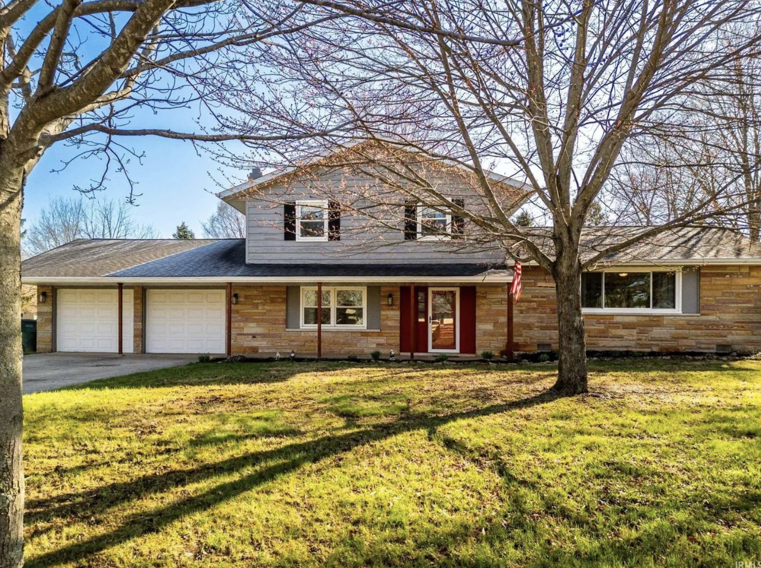 A two-story foreclosed home in Muncie, IN, with a yard and trees