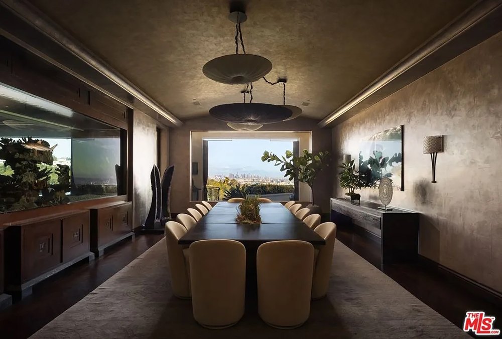 Formal dining room showcasing a massive built-in aquarium wall and a long table overlooking city vistas.