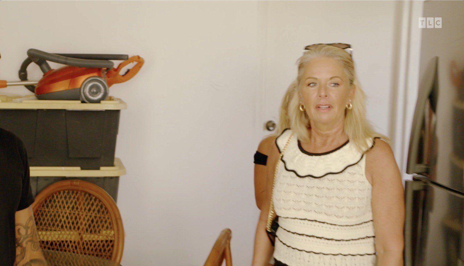 The tour begins in the kitchen, where several plastic storage bins are stacked against the back wall.