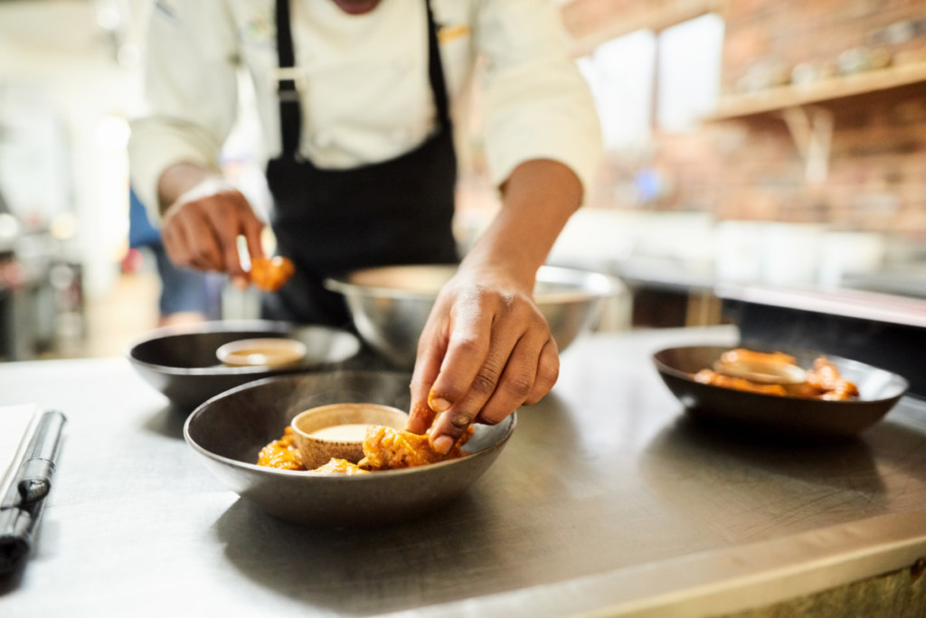 Close-up of male chef arranging food on a dish in the commercial kitchen