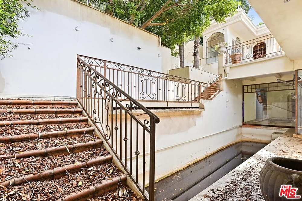 A Graffiti-Covered Mansion Is Back on the Market with a Starting Bid of $2.2 Million Outdoor Staircase with Wrought Iron Railings Leading Down to Pool Area