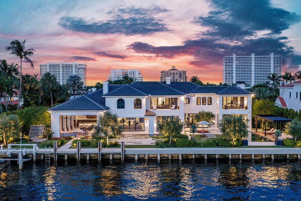 Waterfront View of Luxury Two-Story Estate Illuminated at Sunset