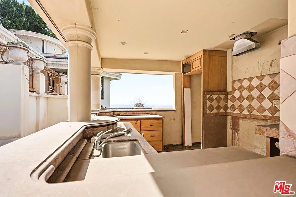 A Graffiti-Covered Mansion Is Back on the Market with a Starting Bid of $2.2 Million Undercover Outdoor Kitchen with Tile Backsplash and Built-In Bar Counters