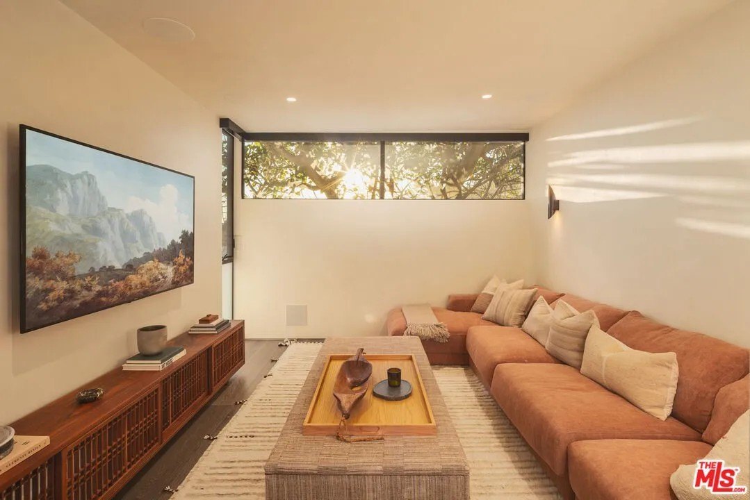 Living space with a large coral colored couch in a luxury home in Malibu owned by Gal Gadot