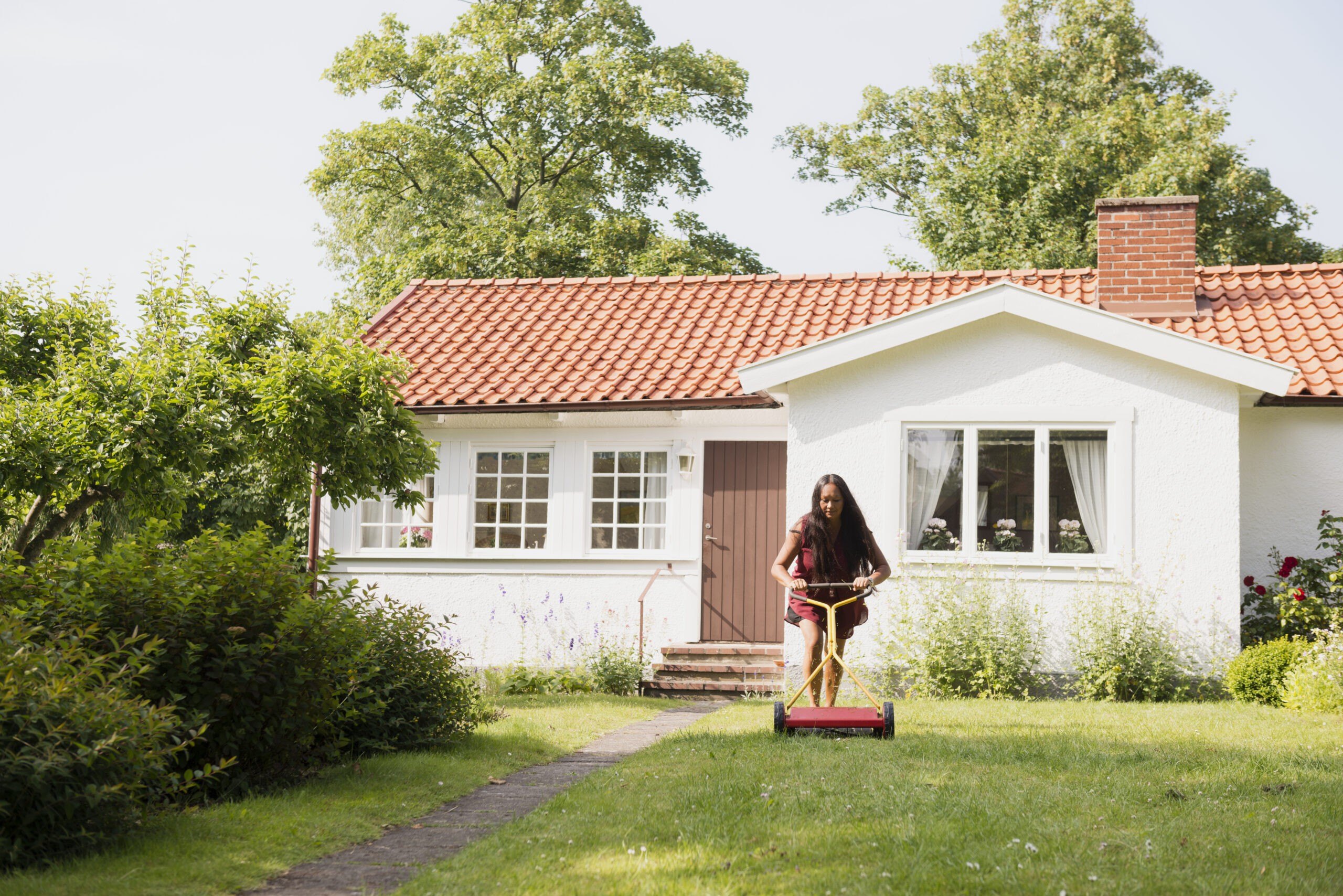 Woman mowing lawn in garden