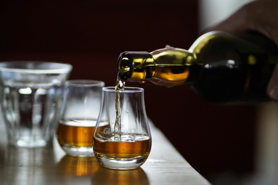 A hand pours whiskey into a glass
