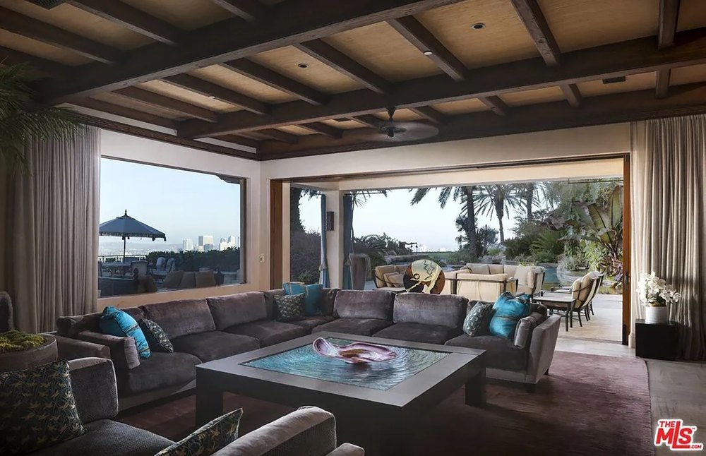 Sophisticated modern lounge with plush sectional seating, a unique coffee table, and pocket doors opening to the patio.
