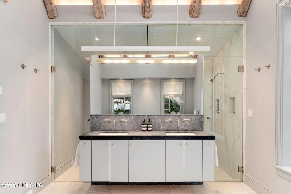 Double sink counter with lights and a large mirror behind it at Chris Simms equestrian estate in Greenwich Connecticut