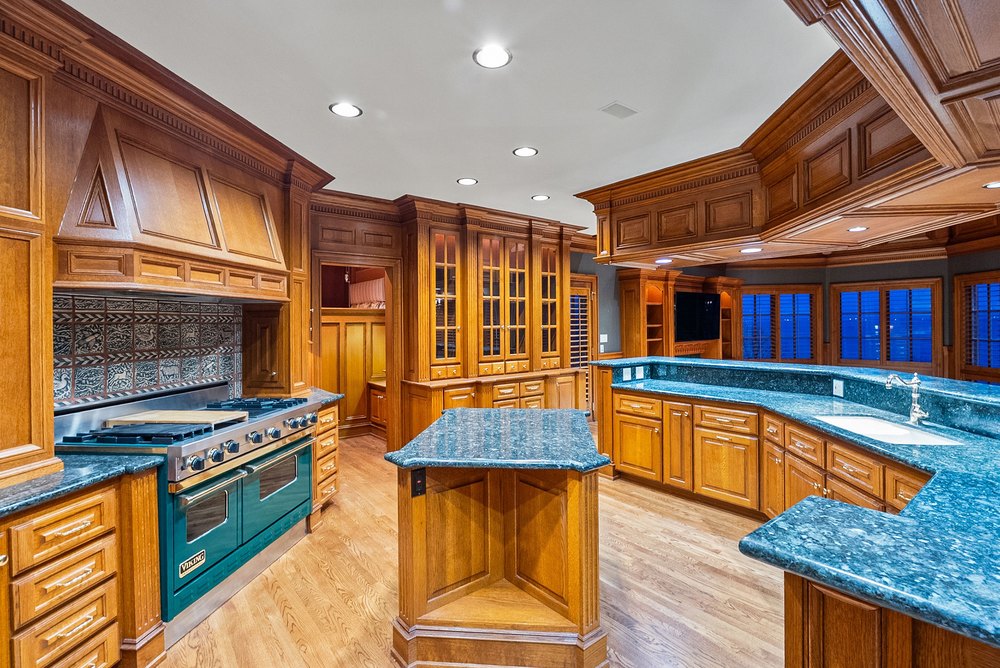 Luxury Kitchen with Custom Wood Cabinetry, Teal Granite Countertops, and Viking Range